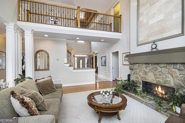 living room with a towering ceiling, ornamental molding, a fireplace, and hardwood / wood-style floors