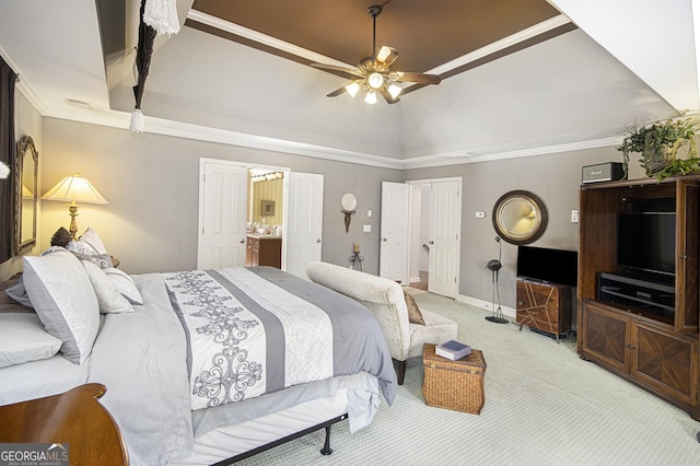 carpeted bedroom with crown molding, ceiling fan, ensuite bathroom, and a tray ceiling