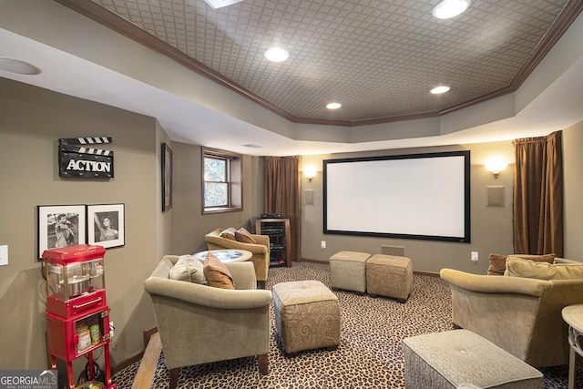 cinema room with a tray ceiling, crown molding, and carpet floors