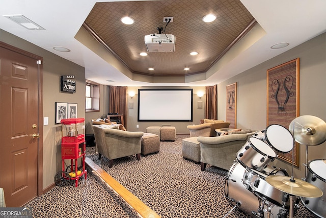 cinema room featuring a raised ceiling, ornamental molding, and hardwood / wood-style flooring