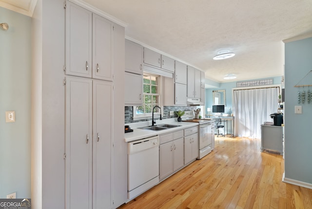 kitchen featuring sink, backsplash, crown molding, white appliances, and light hardwood / wood-style flooring