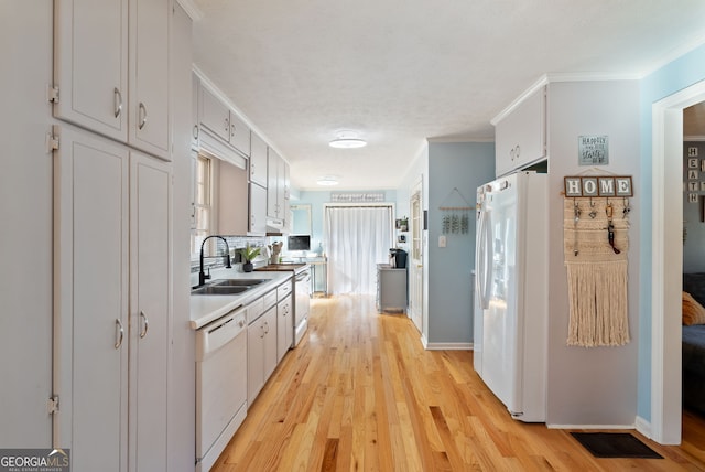 kitchen with sink, crown molding, white appliances, light hardwood / wood-style floors, and white cabinets