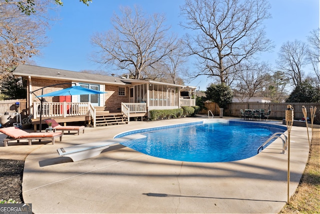 view of swimming pool with a patio, a sunroom, a diving board, and a deck