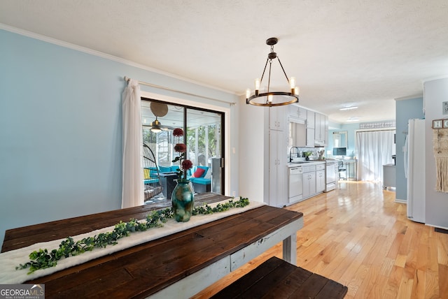 dining area featuring a notable chandelier, ornamental molding, sink, and light wood-type flooring