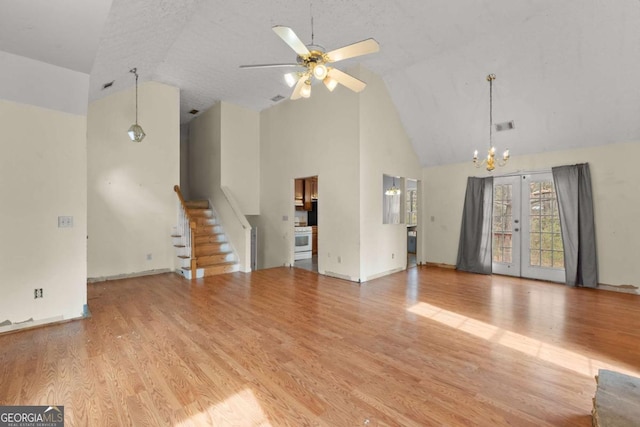 unfurnished living room featuring french doors, high vaulted ceiling, a textured ceiling, light hardwood / wood-style floors, and ceiling fan with notable chandelier