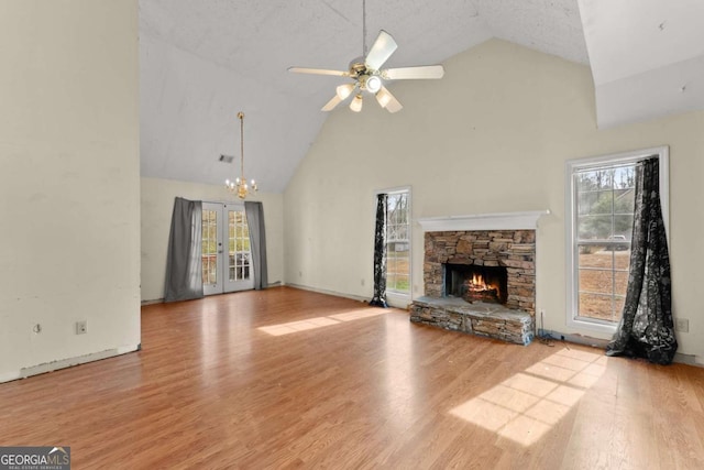 unfurnished living room featuring french doors, high vaulted ceiling, light wood-type flooring, ceiling fan, and a fireplace