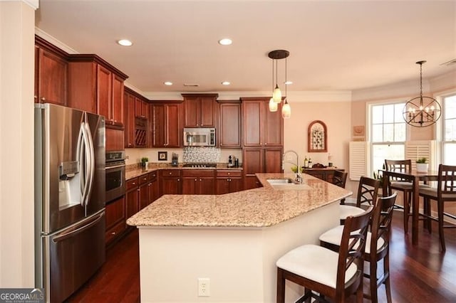 kitchen featuring pendant lighting, appliances with stainless steel finishes, a kitchen island with sink, and sink