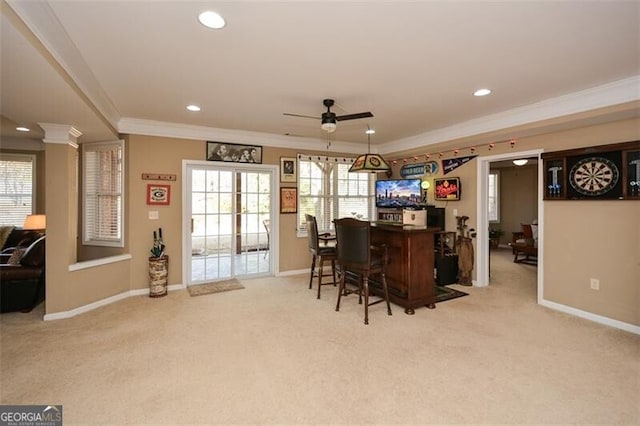 bar with decorative columns, ornamental molding, light carpet, and ceiling fan