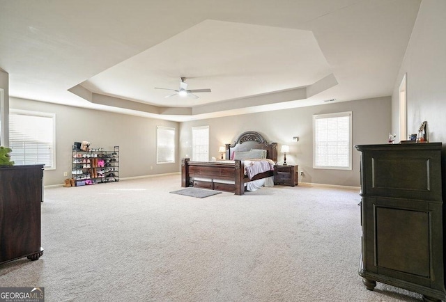 carpeted bedroom featuring ceiling fan and a raised ceiling