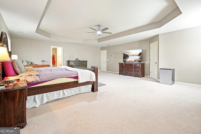 bedroom featuring light carpet, a tray ceiling, and ceiling fan