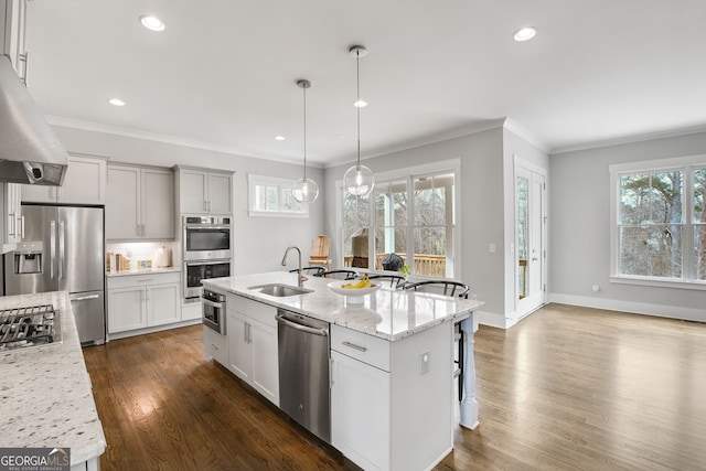 kitchen featuring sink, light stone counters, pendant lighting, stainless steel appliances, and a kitchen island with sink