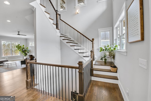 stairs with hardwood / wood-style flooring and ceiling fan