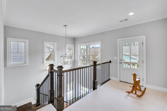 hall featuring ornamental molding, carpet floors, and a notable chandelier