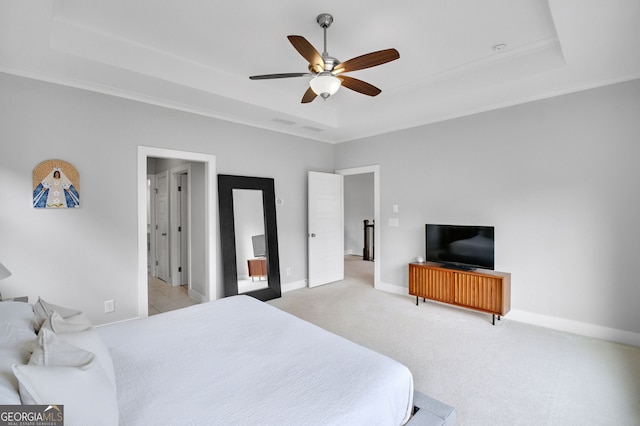 bedroom with light carpet, ceiling fan, and a tray ceiling