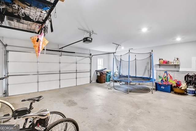 garage with a garage door opener and a trampoline