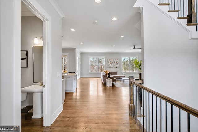 hallway with ornamental molding and light hardwood / wood-style floors