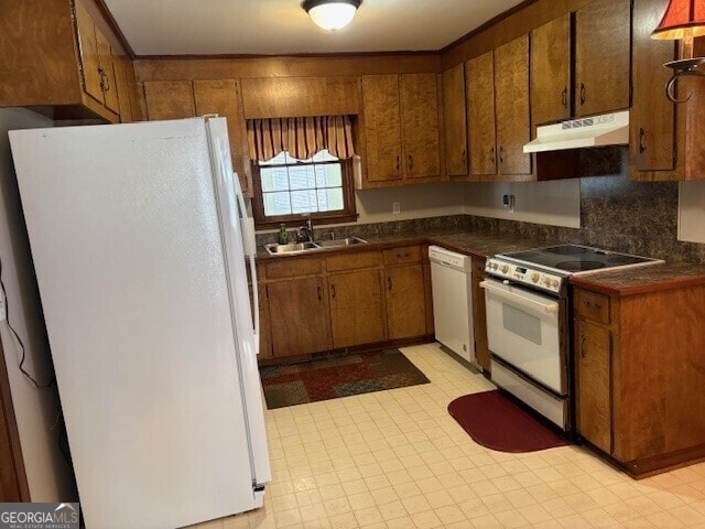 kitchen featuring light floors, brown cabinetry, a sink, white appliances, and under cabinet range hood