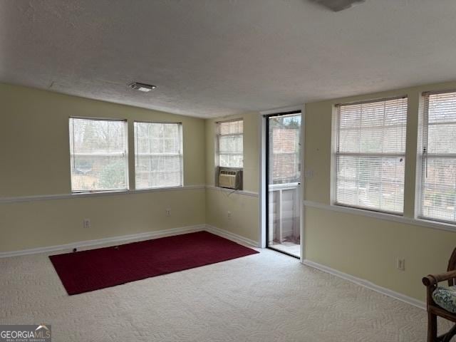 unfurnished room with baseboards, light colored carpet, vaulted ceiling, cooling unit, and a textured ceiling