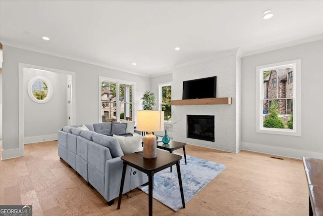 living room featuring crown molding, a brick fireplace, and light hardwood / wood-style flooring