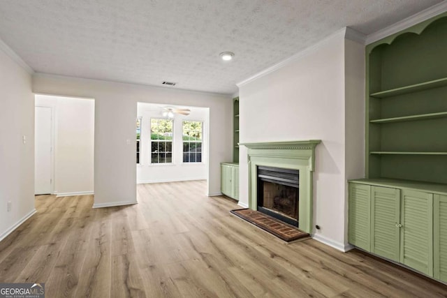 unfurnished living room featuring built in shelves, light hardwood / wood-style flooring, ornamental molding, and a textured ceiling