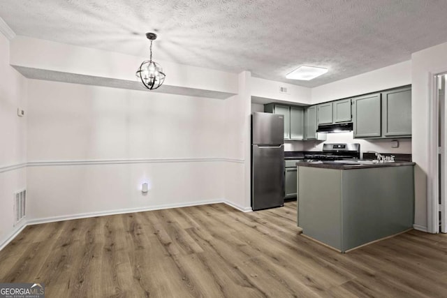 kitchen featuring an inviting chandelier, hardwood / wood-style floors, stainless steel appliances, a textured ceiling, and decorative light fixtures