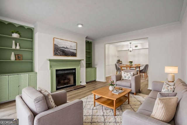 living room with ornamental molding, built in shelves, and light hardwood / wood-style flooring