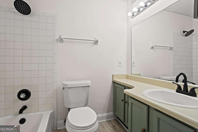 full bathroom with vanity, hardwood / wood-style floors, tiled shower / bath, and toilet