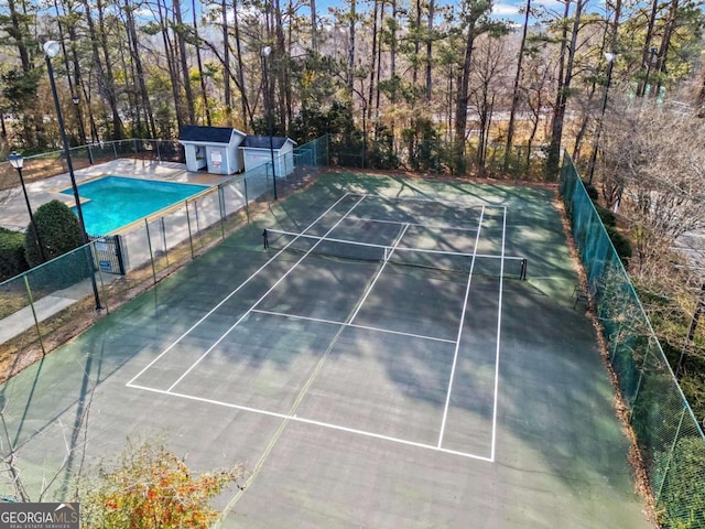 view of tennis court with a fenced in pool