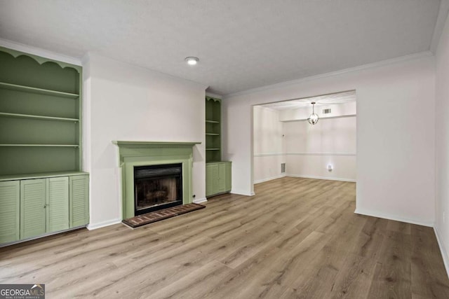 unfurnished living room featuring crown molding, light hardwood / wood-style floors, and built in shelves