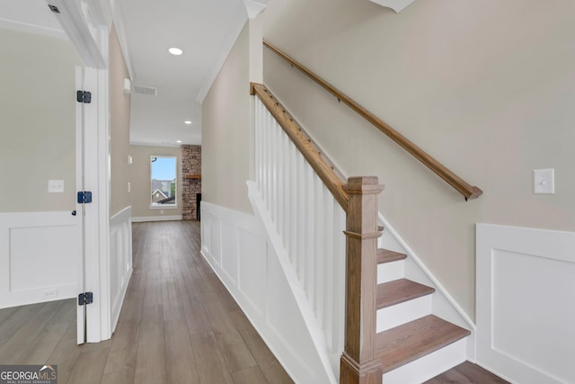 stairs with hardwood / wood-style flooring and a stone fireplace