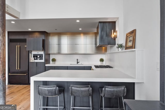 kitchen featuring gray cabinetry, paneled refrigerator, a breakfast bar area, and kitchen peninsula