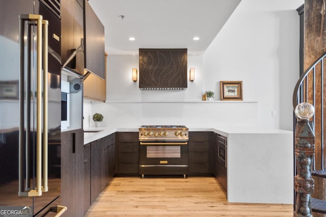 kitchen with light hardwood / wood-style flooring, stainless steel gas range, dark brown cabinetry, high end black fridge, and exhaust hood