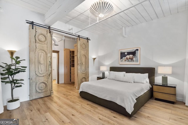 bedroom with wooden ceiling, a barn door, beamed ceiling, and light wood-type flooring