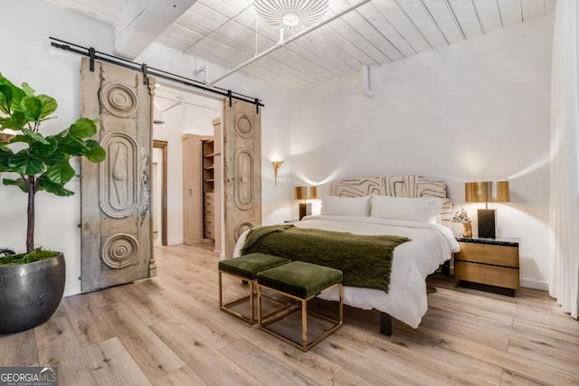 bedroom with wood ceiling, beam ceiling, light hardwood / wood-style floors, and a barn door