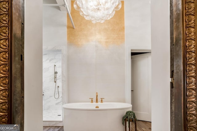 bathroom with hardwood / wood-style flooring, separate shower and tub, and an inviting chandelier