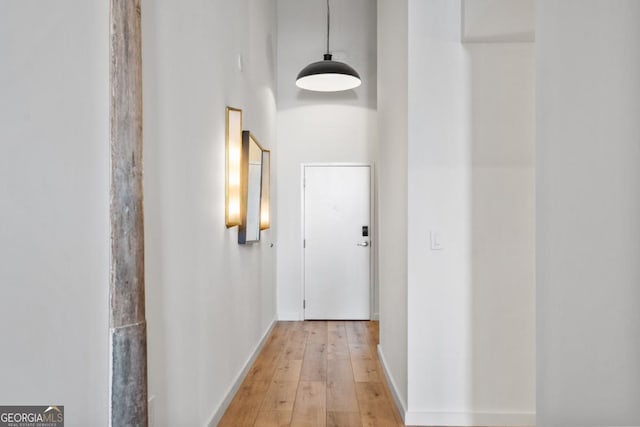 corridor with a towering ceiling and light hardwood / wood-style flooring