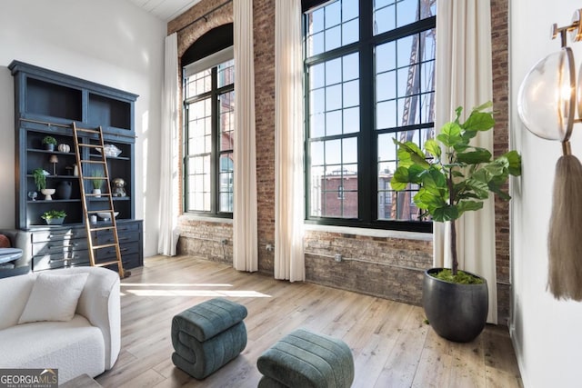 living area with hardwood / wood-style floors and brick wall