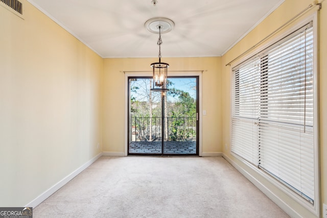 empty room with crown molding, a wealth of natural light, and light colored carpet