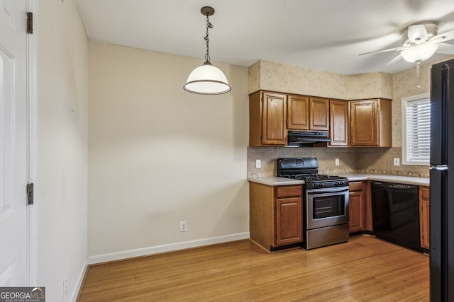 kitchen featuring pendant lighting, range hood, decorative backsplash, light hardwood / wood-style floors, and black appliances