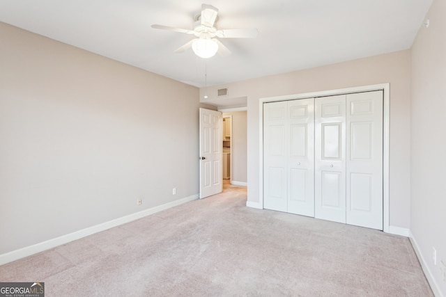 unfurnished bedroom with light colored carpet, ceiling fan, and a closet