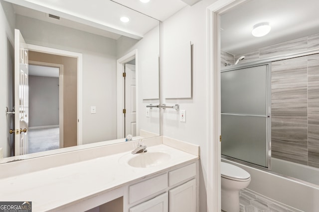 full bathroom featuring vanity, shower / bath combination with glass door, and toilet