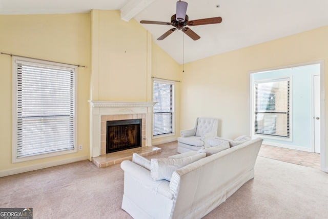 carpeted living room with beamed ceiling, ceiling fan, a tiled fireplace, and high vaulted ceiling