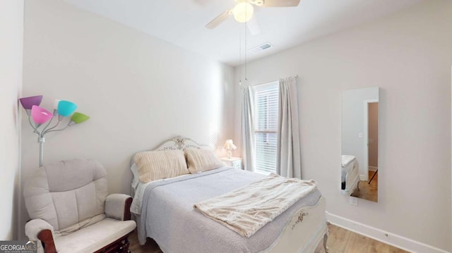 bedroom featuring ceiling fan, light wood finished floors, visible vents, and baseboards