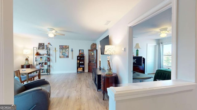 living area featuring visible vents, light wood finished floors, a ceiling fan, and baseboards