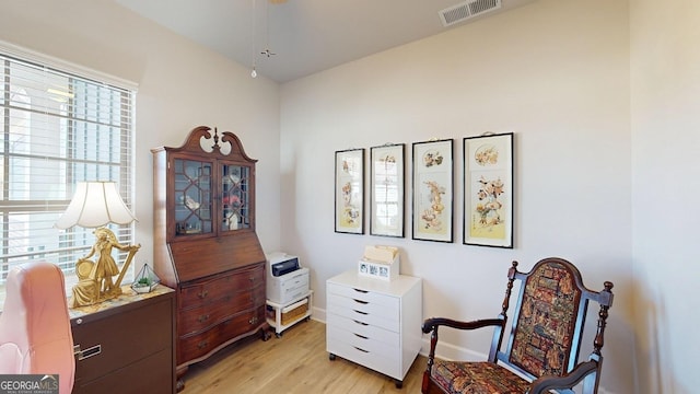 living area with light wood-style floors, visible vents, and baseboards