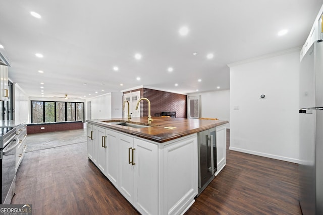 kitchen with sink, wine cooler, white cabinets, a kitchen island with sink, and crown molding