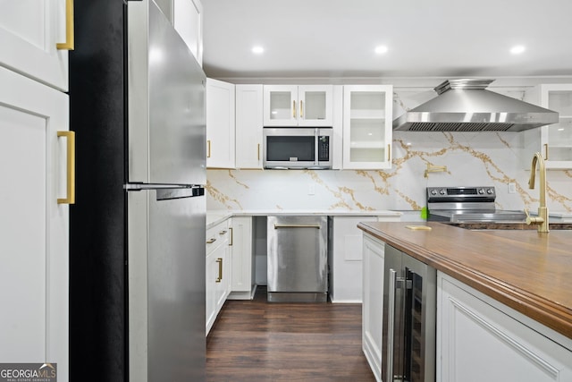 kitchen featuring white cabinetry, range hood, stainless steel appliances, tasteful backsplash, and beverage cooler