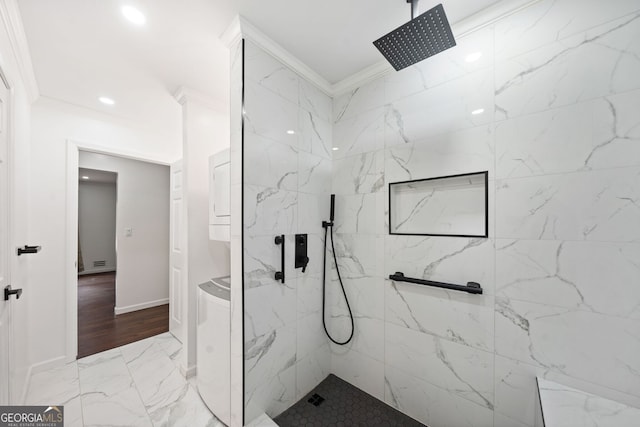 bathroom with tiled shower, ornamental molding, and washer / dryer