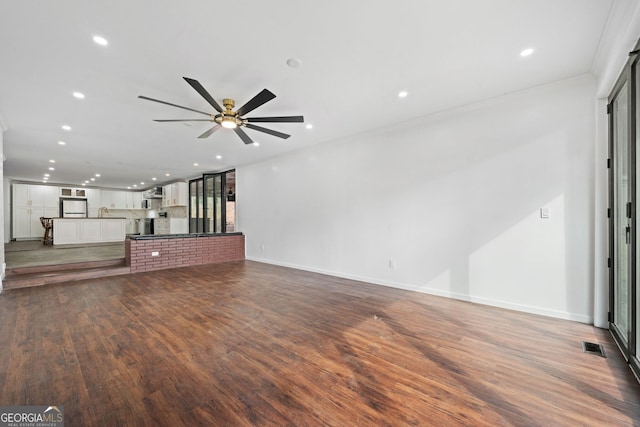 unfurnished living room with ceiling fan, sink, and dark hardwood / wood-style flooring