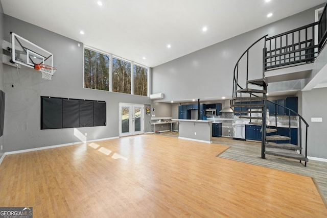 living room featuring french doors, a wall mounted AC, light hardwood / wood-style flooring, and a high ceiling